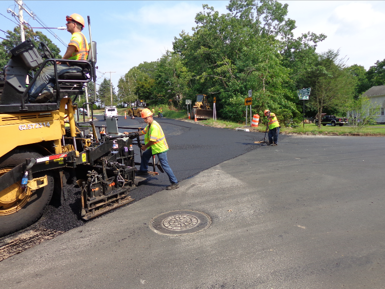 Pave carefully near utility caps to protect paving equipment and to ensure the finished pavement will be sealed beautifully to keep water from getting down into the subbase. For the final lift—the surface course—you can pave over the utility cap. The laborers will clean off the disc itself.