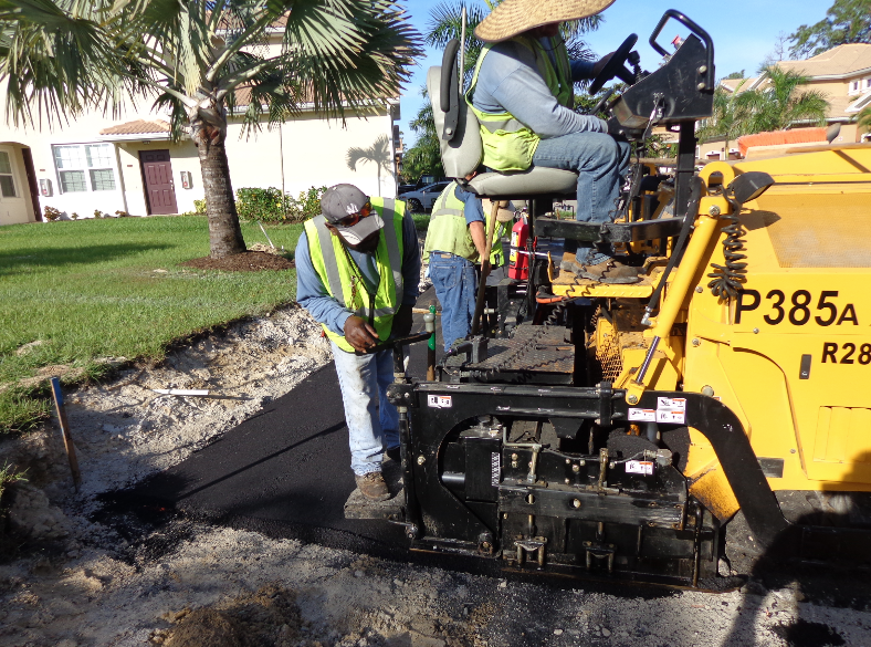 The paver operator sets the screed down on the table, then pulls forward about an inch and a half to tighten the tow arms prior to beginning the pass.