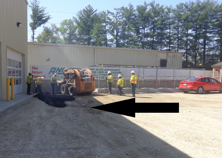 The crew used a skid steer to deliver mix to the small area in the corner to create the pad that the paver will set on to begin its first pull.
