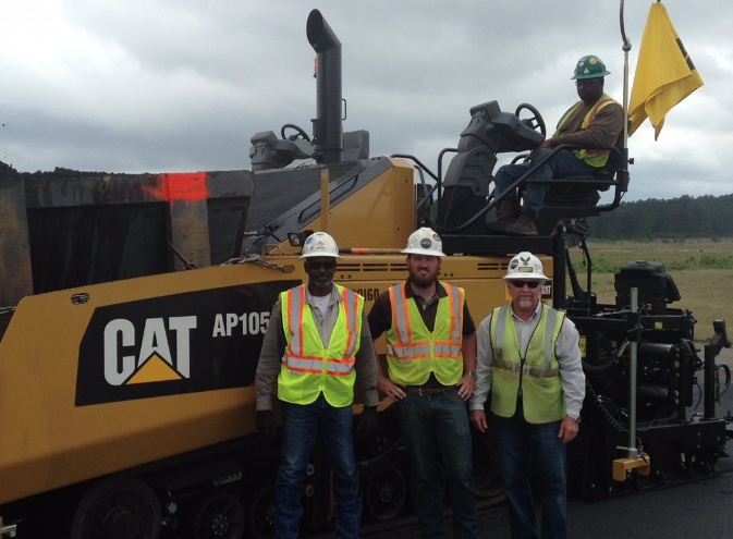From left, Bruce Richardson, Jarred Tarver, Donnie Givens, and paver operator Buck Loyd pose with the Cat AP1055F paver with SE60 V XW vibratory screed at the Polk Army Airfield project.