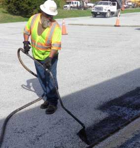 Perform handwork with the wand so you have control of the material. This worker from Boxley places tack precisely along the grate in the United Solutions parking lot. All photos courtesy John Ball, Top Quality Paving & Training, Manchester, New Hampshire.