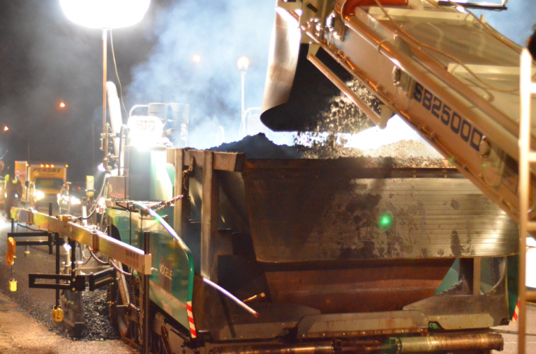 In contrast to the paving crews of 70 years ago, the Lehman-Roberts team employs a Shuttle Buggy feeding a hopper insert to facilitate continuous paving. To help the Shuttle Buggy operator hit his mark, the team has green LEDs strategically mounted on the sides of the paver hopper and shining like a bullseye on the insert’s center. This kind of visual guidance system helps haul truck drivers backing for delivery and helps Shuttle Buggy operators charging hoppers as well.