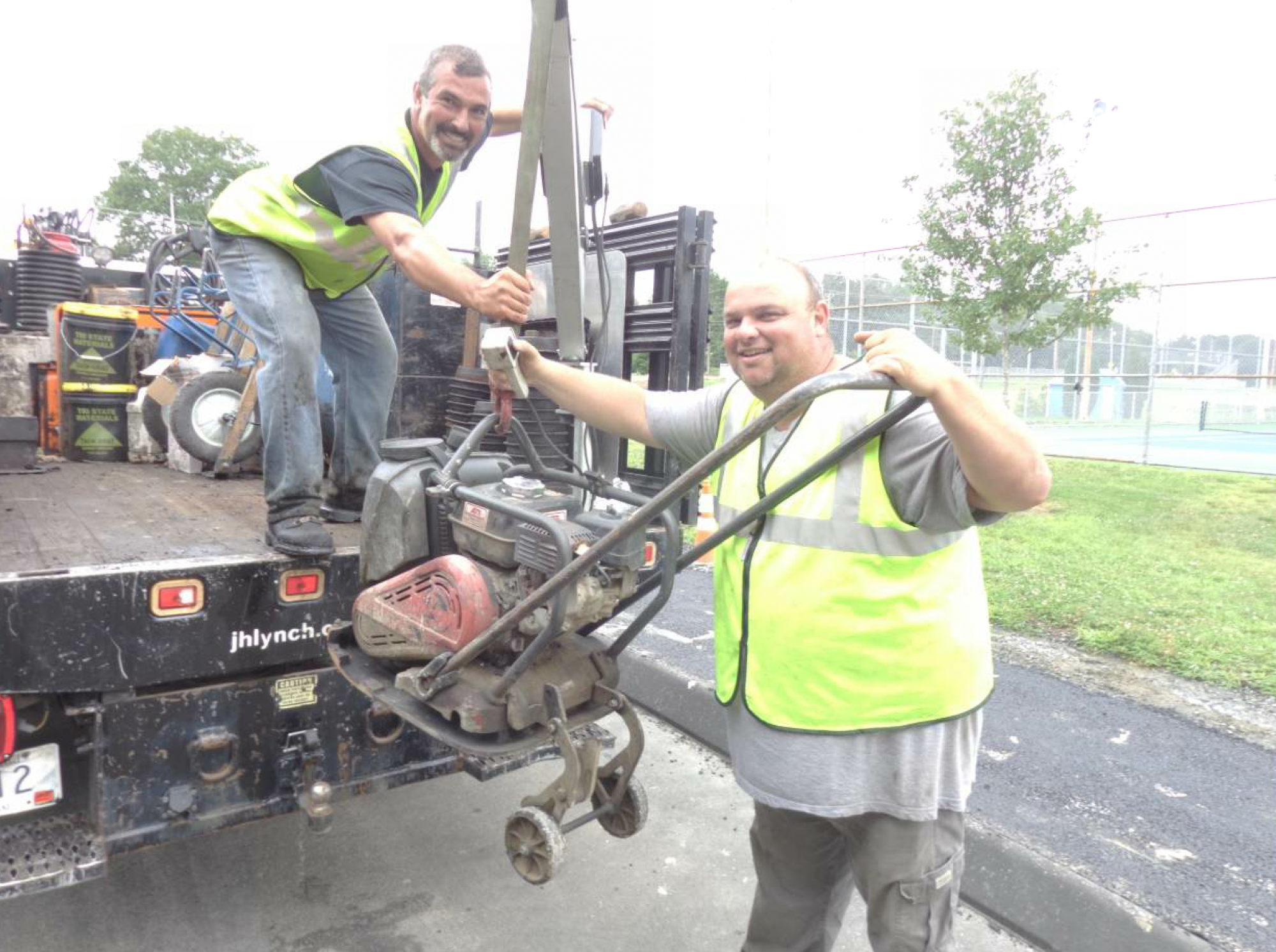 Billy Lopes, who is in the back of the truck, manipulates the crane that brings the plate compactor on board. Greg Pacheco, on the ground, helps guide the plate compactor. Notice the wheels hanging in the “down” position.